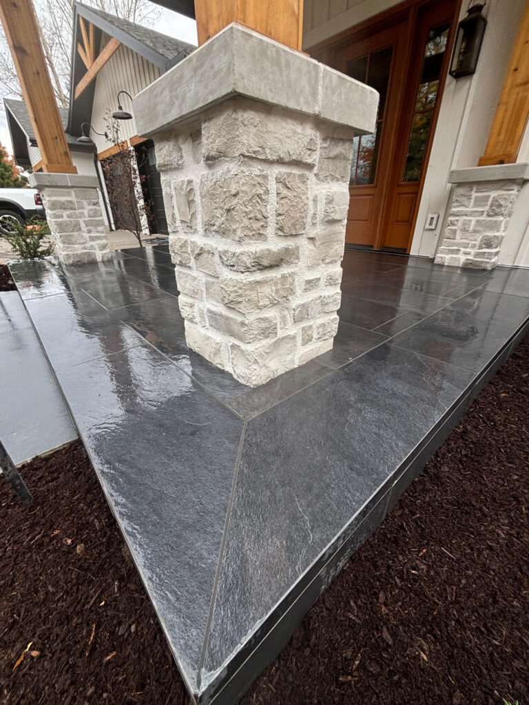 Close-up of front entrance curb appeal in Cambridge, Ontario with black porcelain stone pavers and concrete overlay