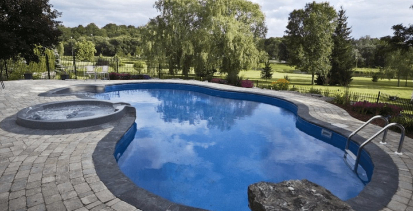 Cambridge home featuring a stunning custom pool with interlocking stone patio, natural stone pool coping, and lush gardens surrounding the area.