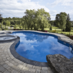 Cambridge home featuring a stunning custom pool with interlocking stone patio, natural stone pool coping, and lush gardens surrounding the area.