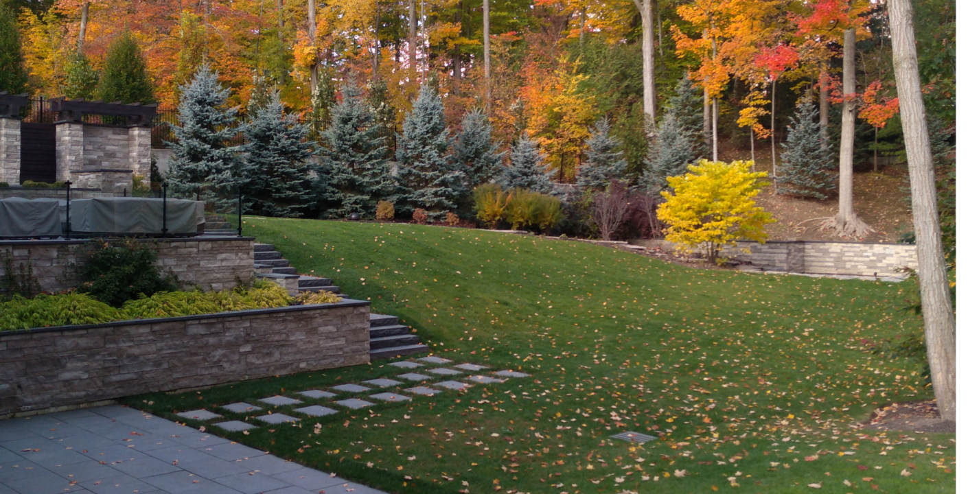 Cambridge Ontario home with hardscaping patio, path, stairs, and retaining wall surrounded by vibrant fall foliage and garden beds.