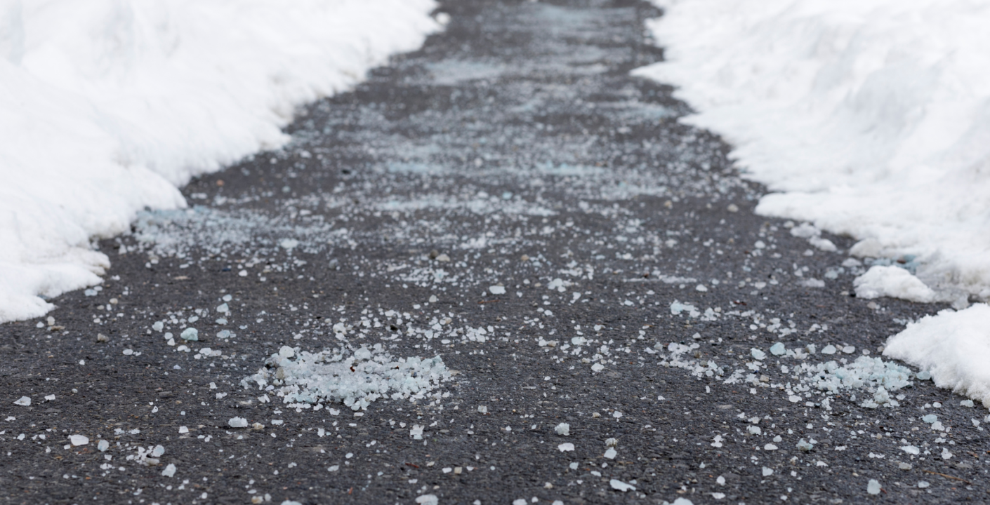 Rock salt sprinkled on a concrete sidewalk for ice prevention in winter.