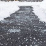Rock salt sprinkled on a concrete sidewalk for ice prevention in winter.